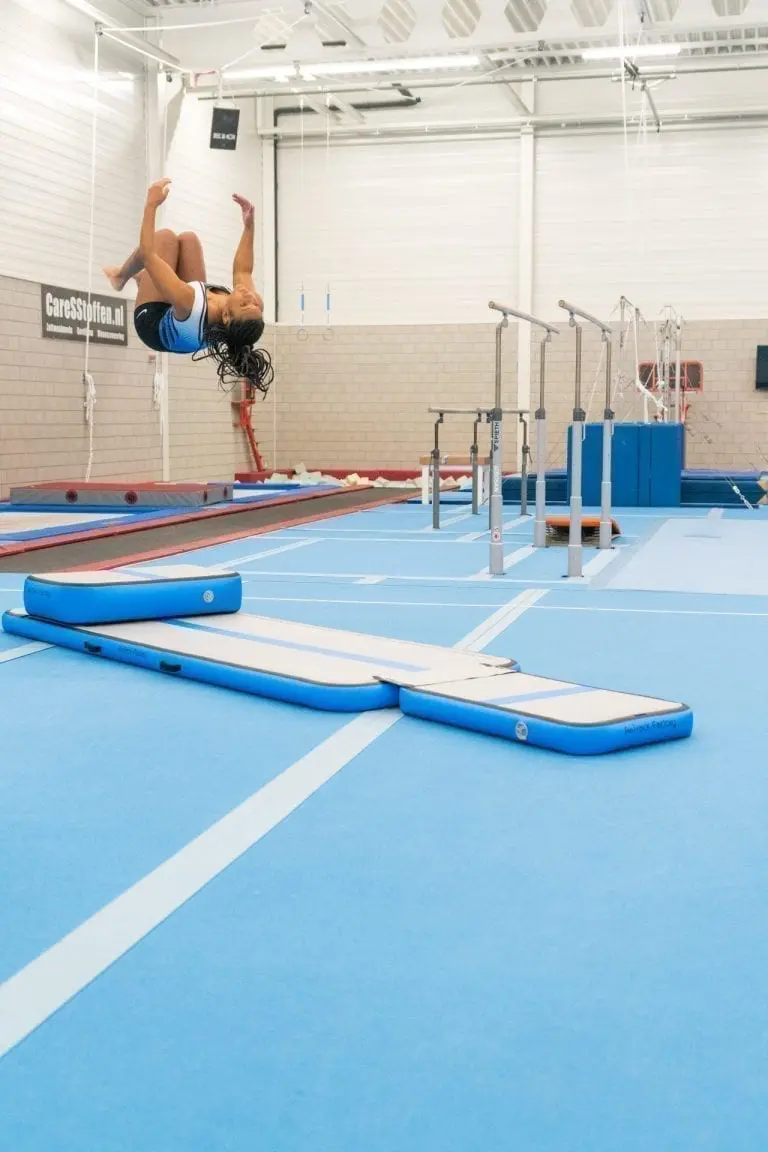 Girl gymnast jumping high on inflatable training set