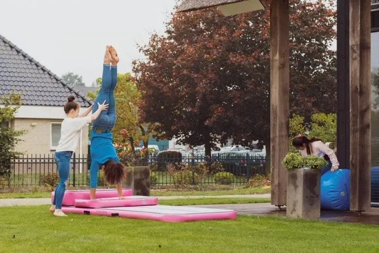 2 girls practicing gymnastics on pink inflatable 3m Air Track training set in garden